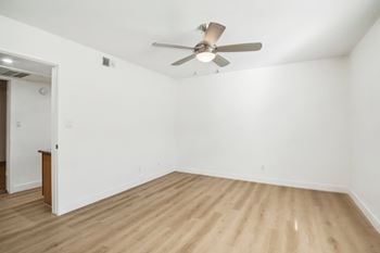 A room with a ceiling fan and wooden flooring.